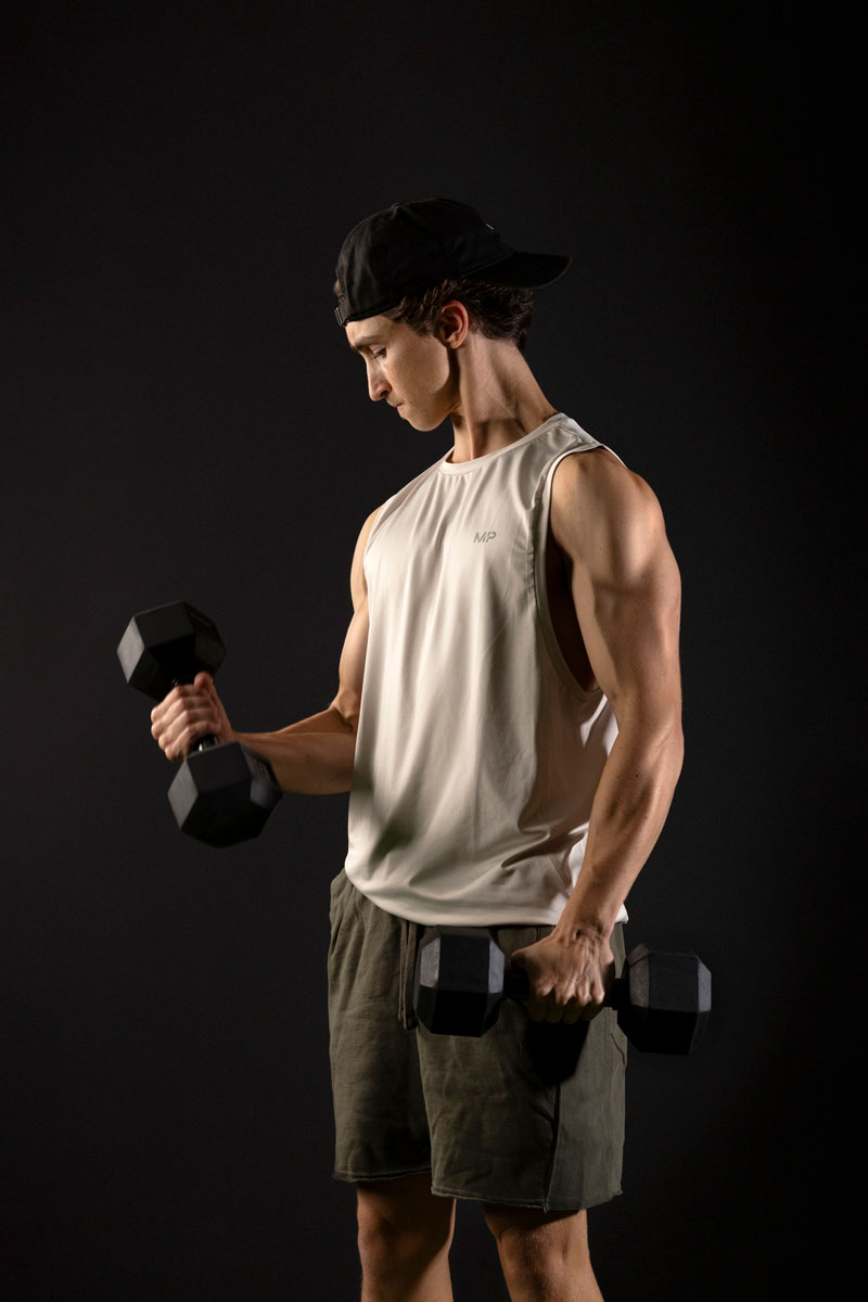 The coach is holding the dumbelles.